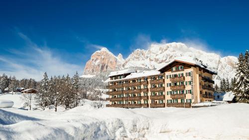 een gebouw bedekt met sneeuw voor een berg bij Hotel Villa Argentina in Cortina dʼAmpezzo