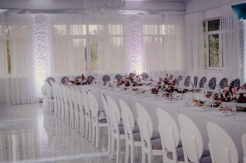 a large white room with a long table with white chairs at База відпочинку "РіверСайд" СВІТЛО Є ЗАВЖДИ in Novomoskovsʼk