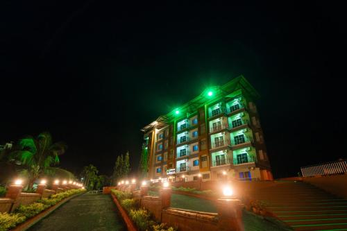 a tall building with green lights on it at night at Treebo Green Village Resort - Goa in Maneri