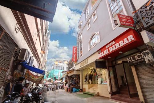 een groep mensen die door een straat met gebouwen lopen bij Hotel Delhi Darbar in New Delhi