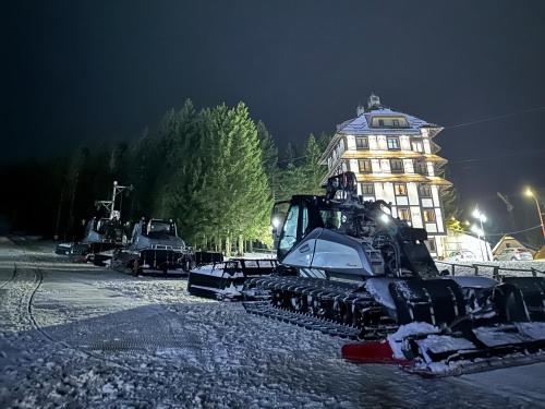 un bulldozer garé dans la neige devant un bâtiment dans l'établissement VILA JEZERO, à Kopaonik