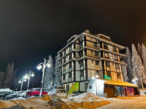 un grand bâtiment dans un parking avec de la neige au sol dans l'établissement VILA JEZERO, à Kopaonik