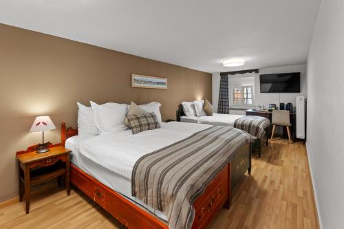 a hotel room with two beds and a desk at Le Saint Georges in Gruyères