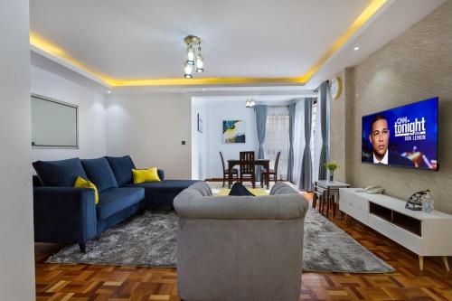 un salon avec un canapé bleu et une télévision dans l'établissement Tranquil Residences, à Nairobi