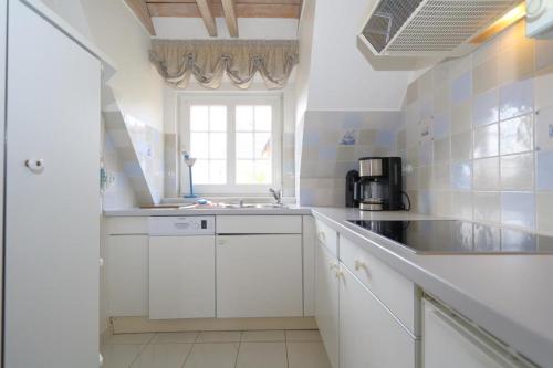 a white kitchen with a sink and a window at Syltnest in Munkmarsch