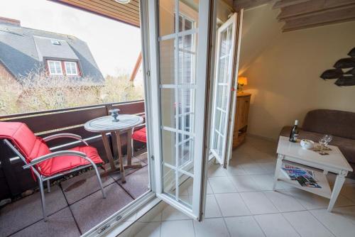 a room with a balcony with a table and chairs at Syltnest in Munkmarsch