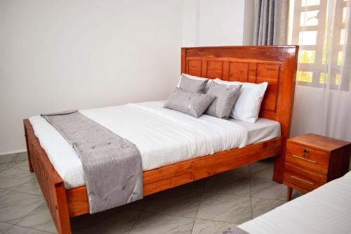 um quarto com uma cama de madeira com lençóis e almofadas brancos em Mzinyi Homes em Voi