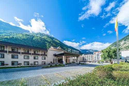 um edifício com uma montanha ao fundo em Qianhe Rezen Hotel em Jiuzhaigou