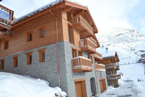 ein Gebäude im Schnee vor einem Berg in der Unterkunft Chalet Le Quartz in Val Thorens