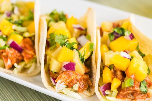 dos tacos en un plato blanco con ensalada de frutas en The Laylow, Autograph Collection, en Honolulu