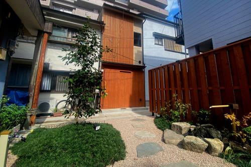 einen Garten vor einem Haus mit einem Zaun in der Unterkunft 2024年10月Open! 8坪の小さな宿と11坪の庭園 平の宿房 in Kōbe