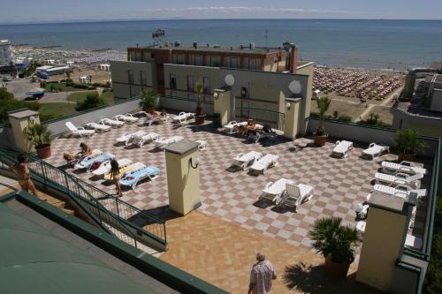 ein Hotel mit einer Terrasse mit Liegestühlen und Meerblick in der Unterkunft Residence Cristoforo Colombo in Caorle