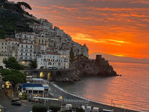 un grupo de edificios al lado de una montaña al atardecer en Holidays Baia D'Amalfi, en Amalfi