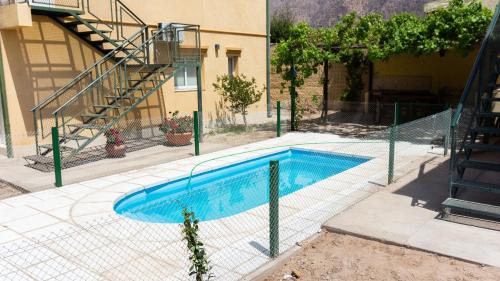 una piscina con una valla junto a un edificio en Departamentos PASEO DE LAS VIÑAS, CAFAYATE, en Cafayate