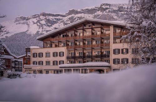 un gran edificio con nieve delante en Hotel Adula, en Flims