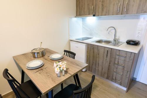 - une cuisine avec une table en bois, des chaises et un évier dans l'établissement Philippos Residences, à Leptokaryá