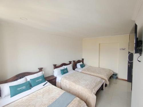 a group of three beds in a room at HOTEL El MONARCA in Tunja