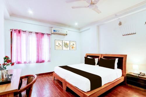 a bedroom with a bed and a table and a desk at Hotel O VG Grand in Madhapur