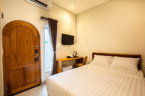 a bedroom with a bed and a wooden door at Baliem CoLiving in Jimbaran