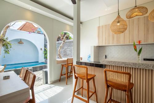 a kitchen with chairs and a bar with a pool in the background at Baliem CoLiving in Jimbaran