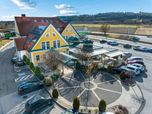 ein großes gelbes Haus mit Autos auf einem Parkplatz in der Unterkunft Rasthaus zum Dokl in Gleisdorf