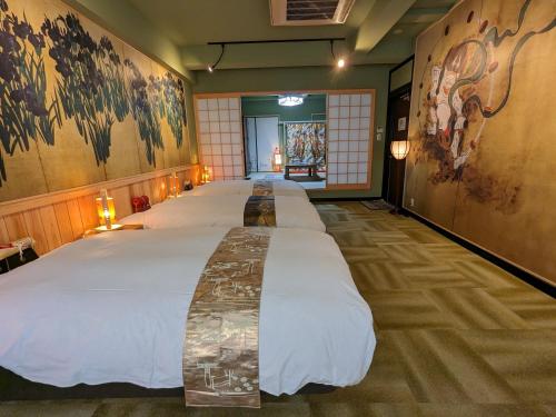 - un grand lit dans une chambre ornée de peintures sur les murs dans l'établissement Osaka Ukiyoe Ryokan, à Osaka