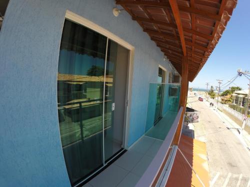 a balcony with glass doors on a building at Xodó do Peró Suítes in Cabo Frio