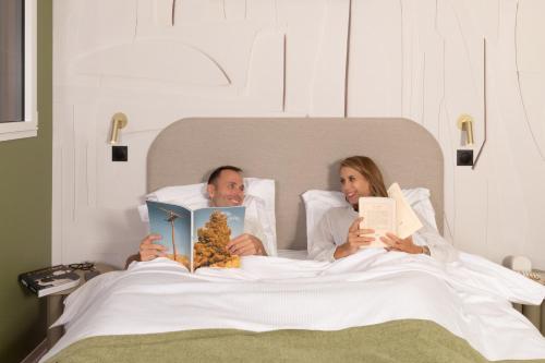 een man en vrouw die in bed liggen boeken te lezen bij Appart Hotel Neostelia in Annecy