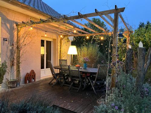 patio con tavolo e sedie su una terrazza in legno di Le Gîte du Puit des Granges a Fontaine-sur-Coole