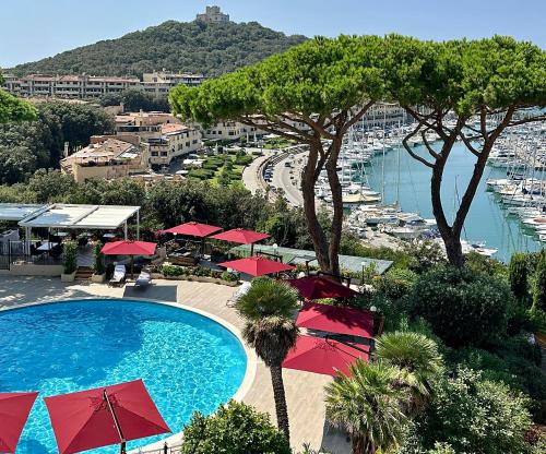 uma piscina com guarda-sóis vermelhos e vista para um porto em Cala del Porto Punta Ala em Punta Ala