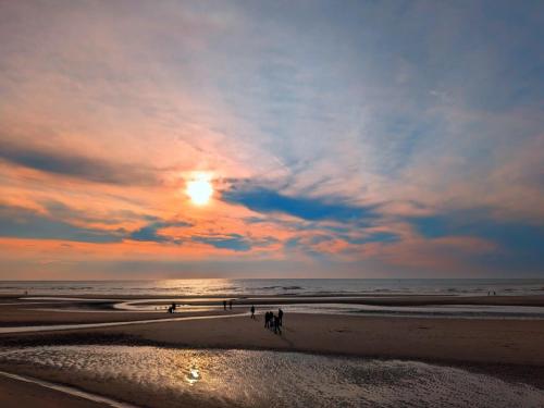 un gruppo di persone che camminano sulla spiaggia al tramonto di San Remo Apartments Blackpool a Blackpool