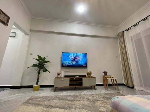 sala de estar con TV de pantalla plana en la pared en Little Rubix 1 Bedroom Apartment, en Dar es Salaam