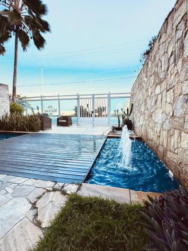 una piscina con una fuente frente a una pared en Mandai Apartamentos, en Cabo Frío