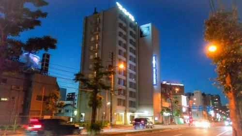 松山Smile Hotel Matsuyama的夜幕降临的城市街道上一座高楼