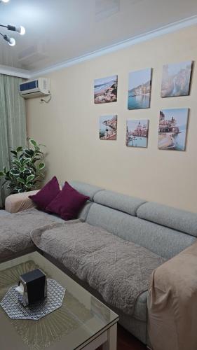 - un salon avec un canapé et des photos sur le mur dans l'établissement 3х апартаменты на Shymkent Plaza, à Chimkent