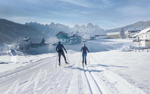 zwei Menschen Langlaufen im Schnee in der Unterkunft COOEE alpin Hotel Dachstein in Gosau