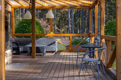 een houten terras met een bank en een tafel en stoelen bij Miško Fėja in Birštonas