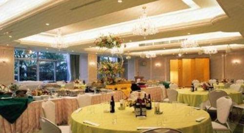 um salão de banquetes com mesas verdes e cadeiras brancas em Kokura Recent Hotel em Kitakyushu