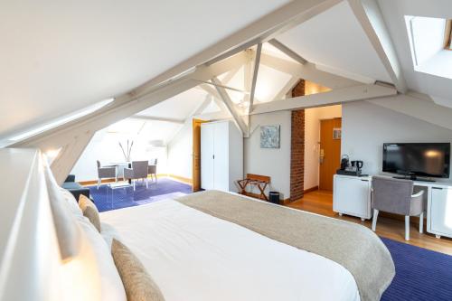 een slaapkamer met een groot bed en een televisie bij Hotel d'Angleterre in Châlons-en-Champagne