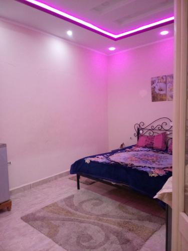 - une chambre avec un lit à éclairage violet dans l'établissement Dar Bilel, à Tozeur