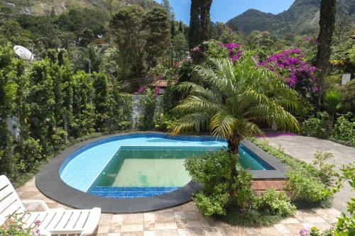 une piscine dans un jardin avec un palmier dans l'établissement Chalé Rosa do Vale, à Petrópolis