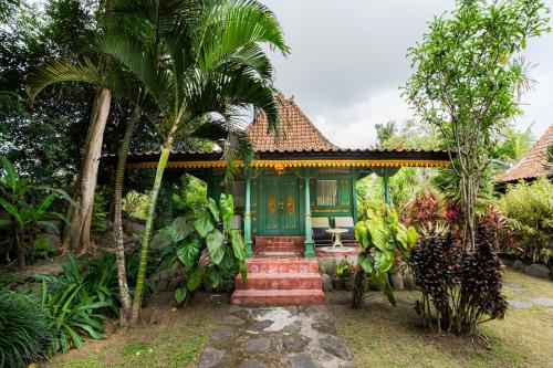 une maison avec une porte verte et des palmiers dans l'établissement The River Island Bali, à Sidemen