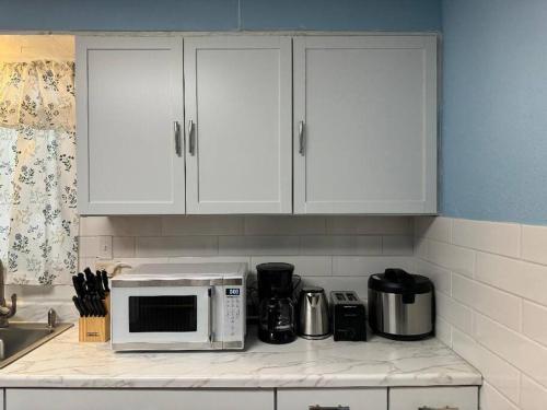 a kitchen with white cabinets and a microwave on a counter at Getaway at Niagara in Niagara Falls