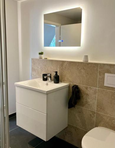 La salle de bains est pourvue d'un lavabo blanc et d'un miroir. dans l'établissement Airport Business Apartment, à Norderstedt