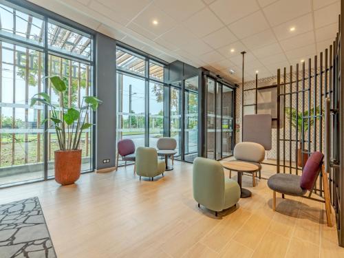 ブレストにあるB&B HOTEL Brest Porte de Gouesnouの椅子、テーブル、窓のある待合室