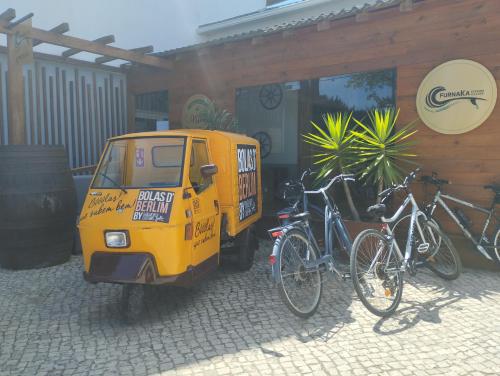 una pequeña furgoneta amarilla estacionada junto a dos bicicletas en Furnaka Eco Village, en Lourinhã