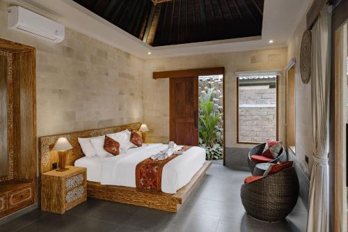 ein Schlafzimmer mit einem Bett und einem Stuhl in der Unterkunft Monique Ubud Villa in Ubud