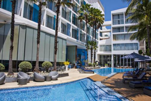 una piscina con palme e un edificio di Hotel Baraquda Heeton Pattaya by Compass Hospitality a Centro di Pattaya