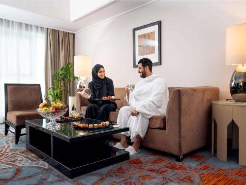 a man and a woman sitting on a couch in a living room at Swissotel Makkah in Makkah