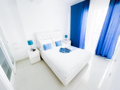 - une chambre blanche avec des rideaux bleus et un lit dans l'établissement DUCASSI Suites ROOMS BEACH playa Bavaro WiFi Parking ROOFTOP POOL SPA, à Punta Cana